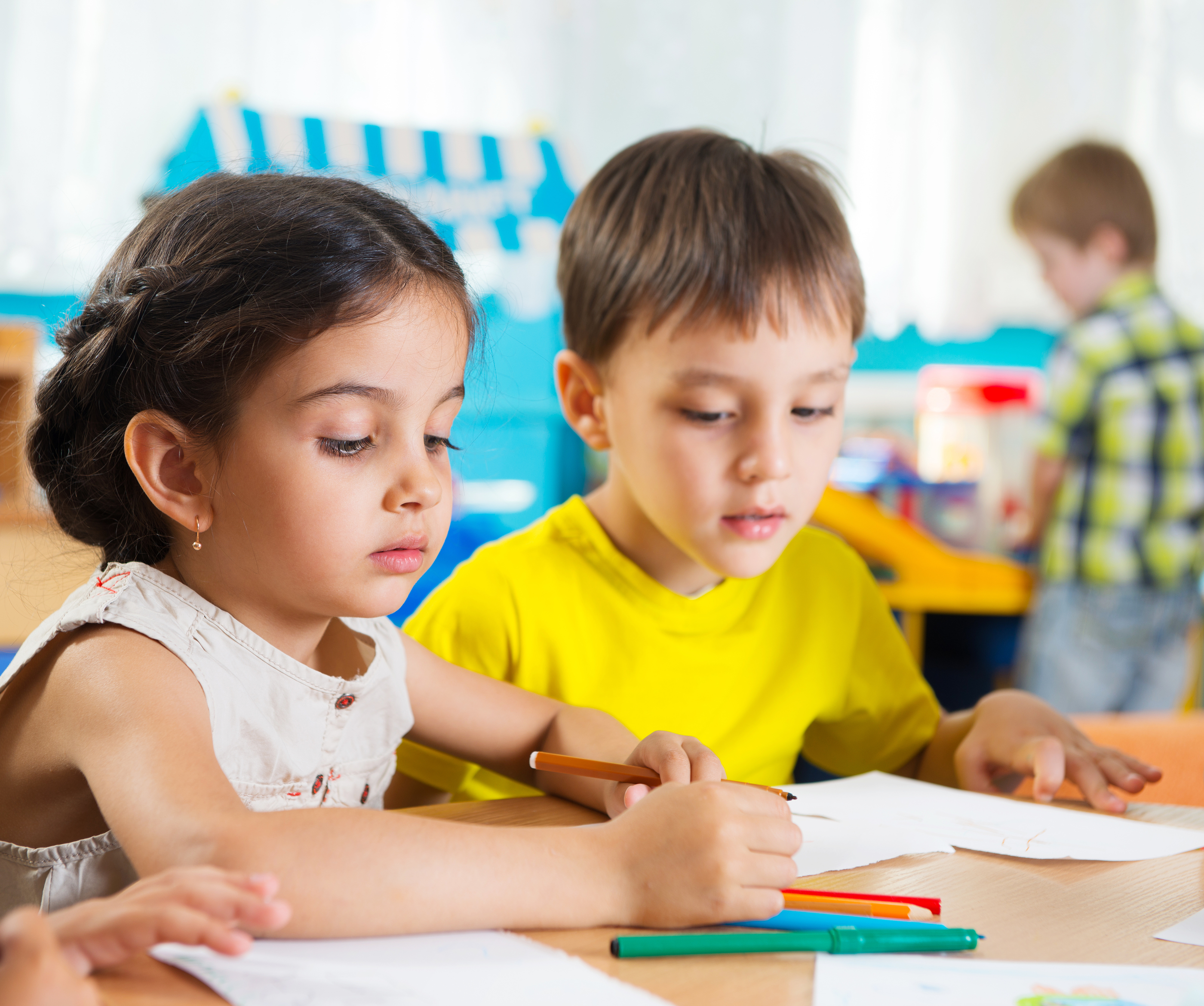 Cute preschoolers drawing with colorful pencils at daycare